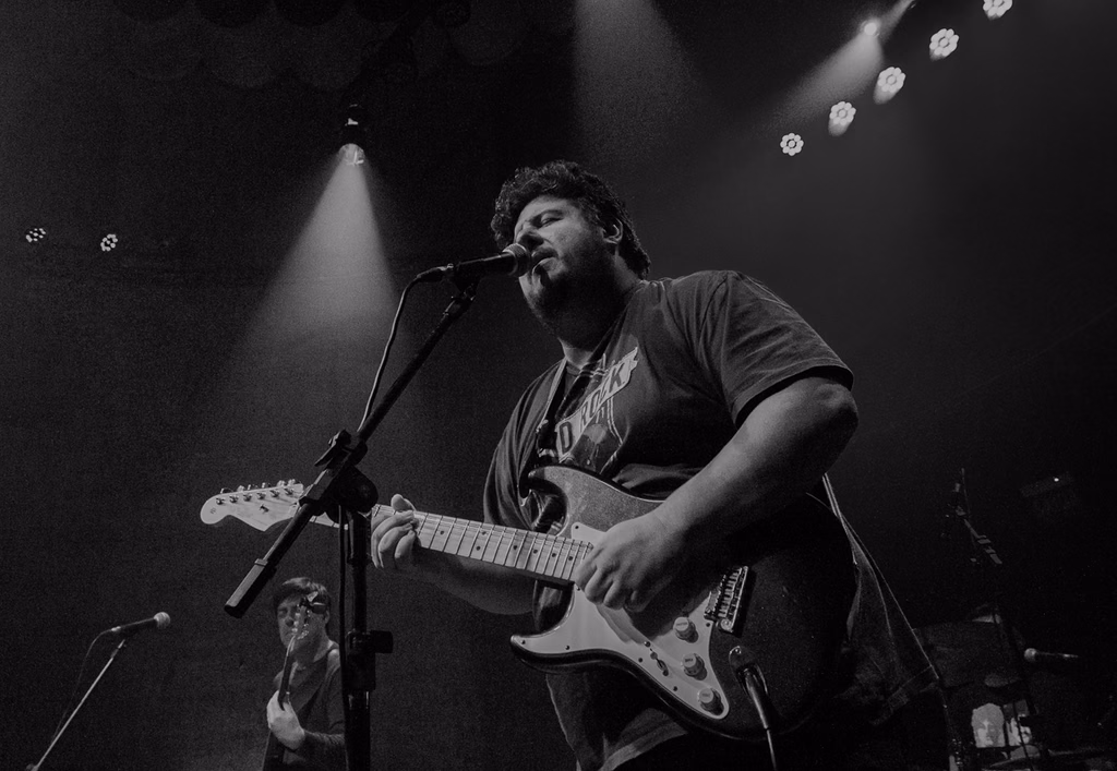 International blues guitarist performing live on stage, singing into the microphone and playing guitar during the show.